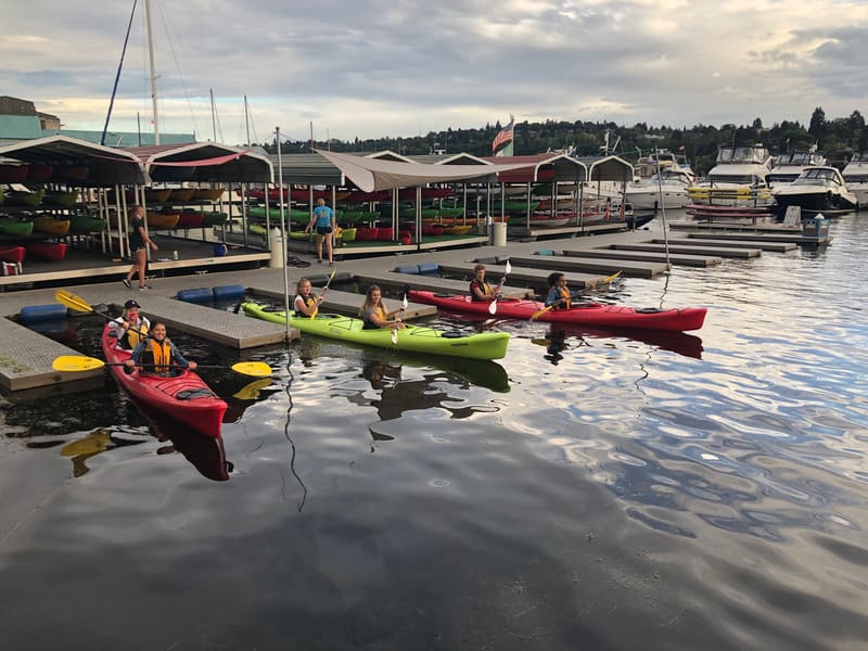 Team kayaking on the lake beside a marina