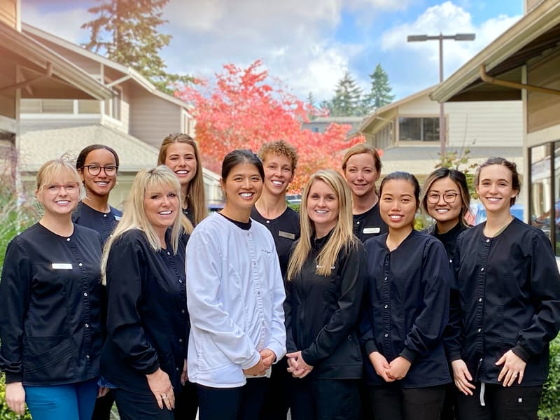 Team in matching scrubs outdoors under autumn trees