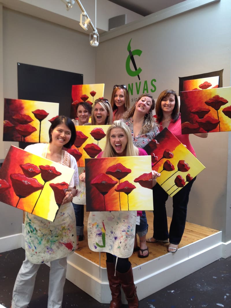 Team holding their paintings after a painting class
