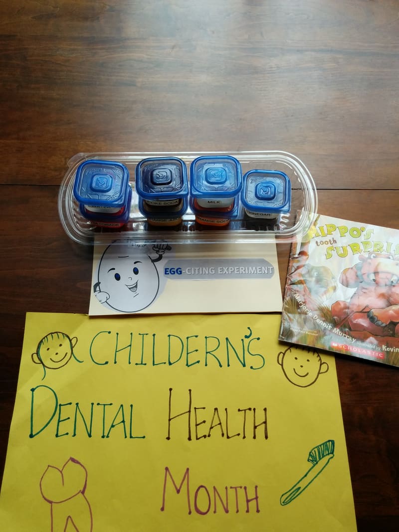 Children's Dental Health Month sign with toothbrush kits