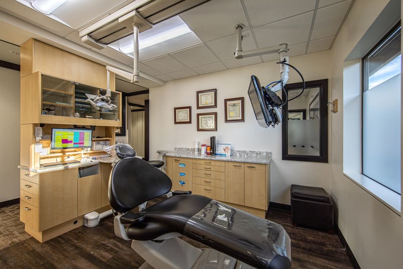 Treatment room with a dental chair, wood cabinetry and framed pictures